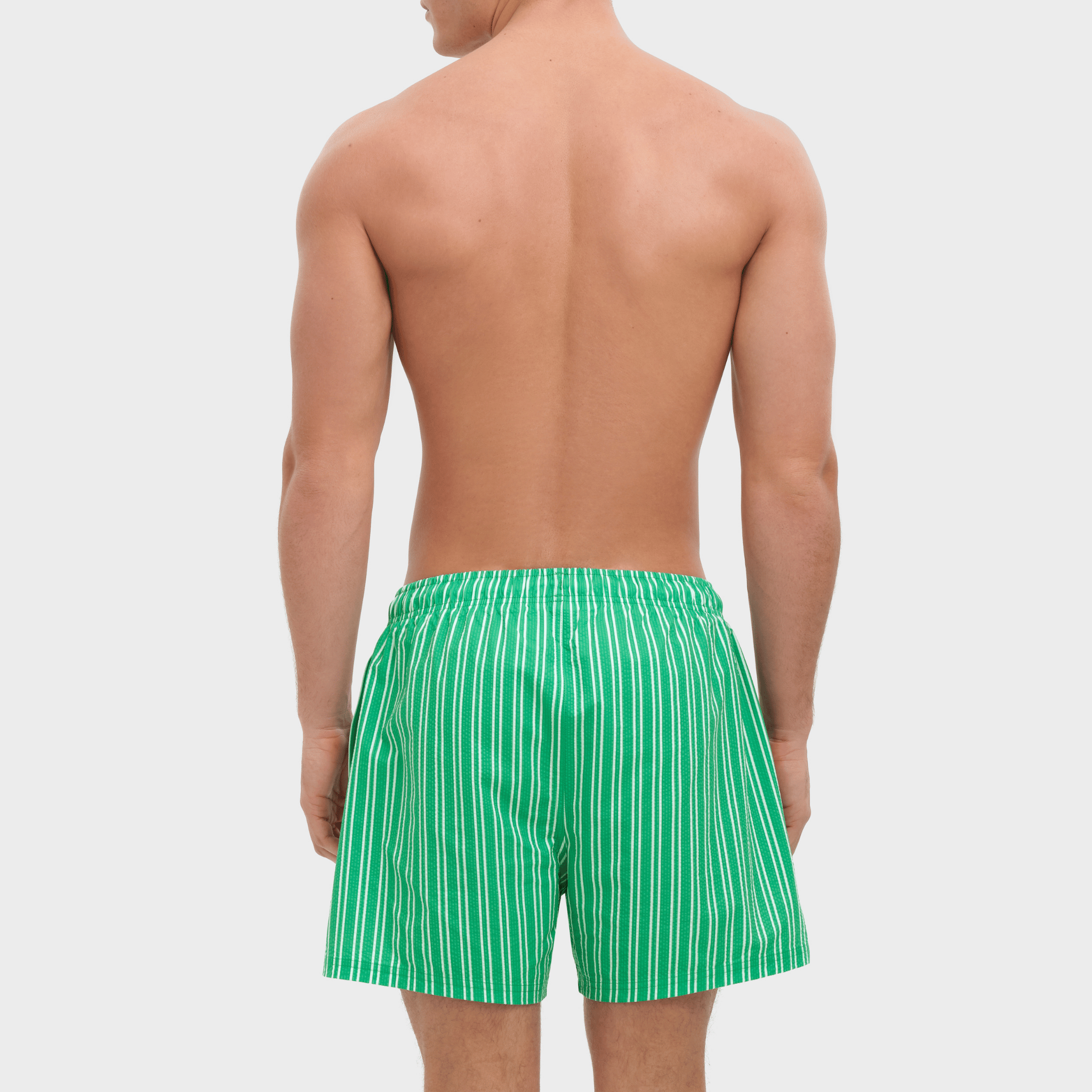 Man wearing green striped swim shorts on a white background
