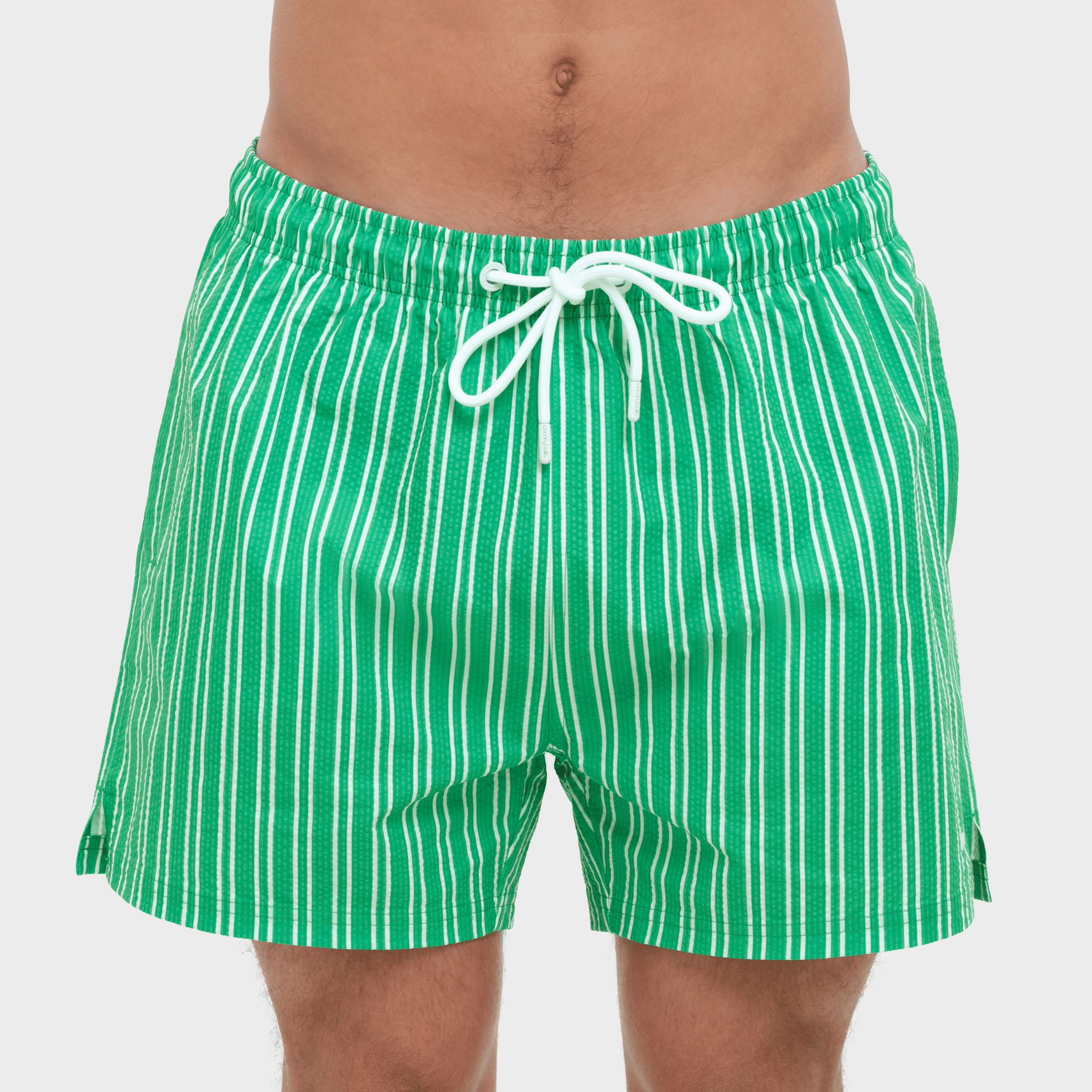 Green and white striped swim shorts on a plain background