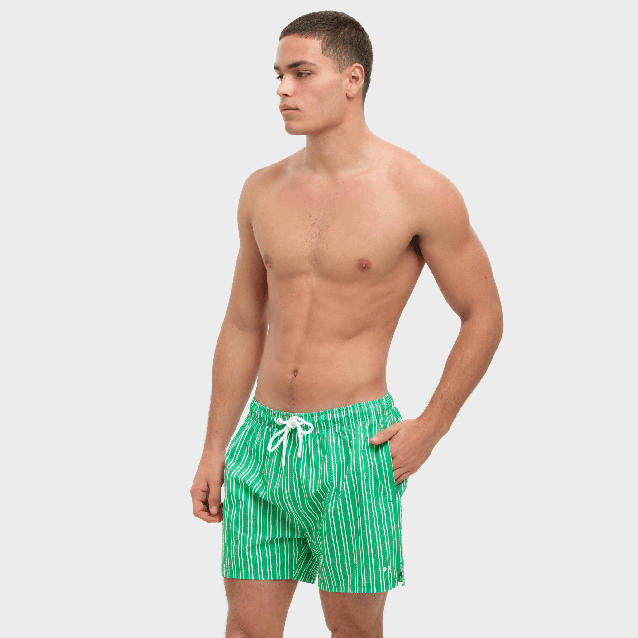 Man wearing green striped swim shorts on a white background
