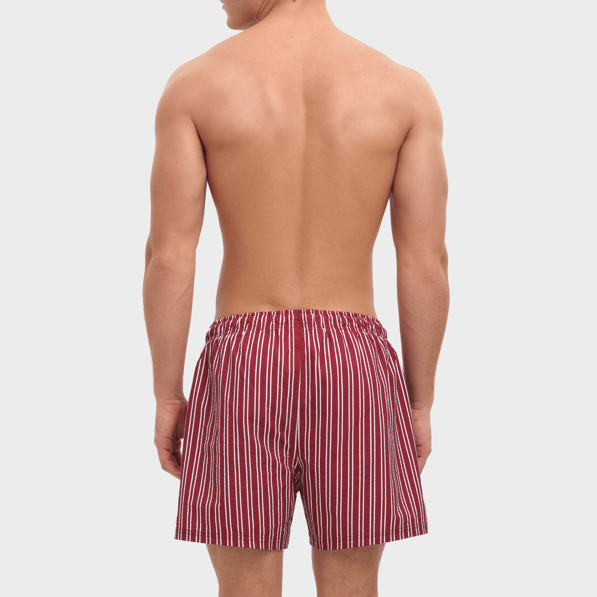 Person wearing red and white striped boxer shorts on a plain background