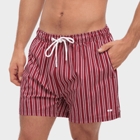 Red and white striped swim shorts worn by a person on a plain background