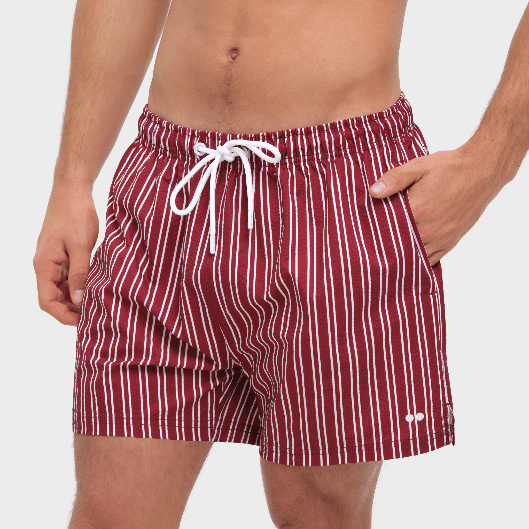 Red and white striped swim shorts worn by a person on a plain background