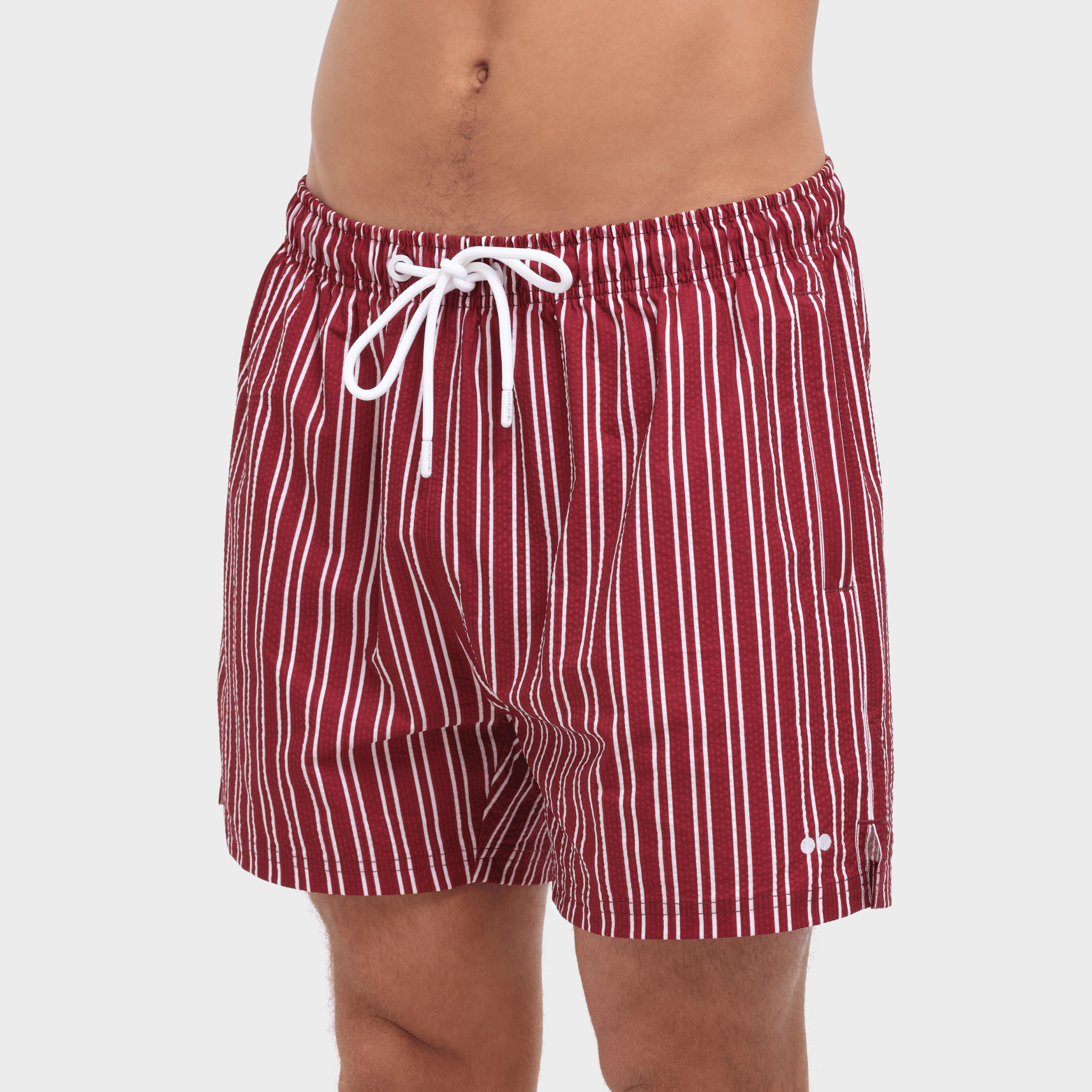 Red and white striped swim shorts on a plain background