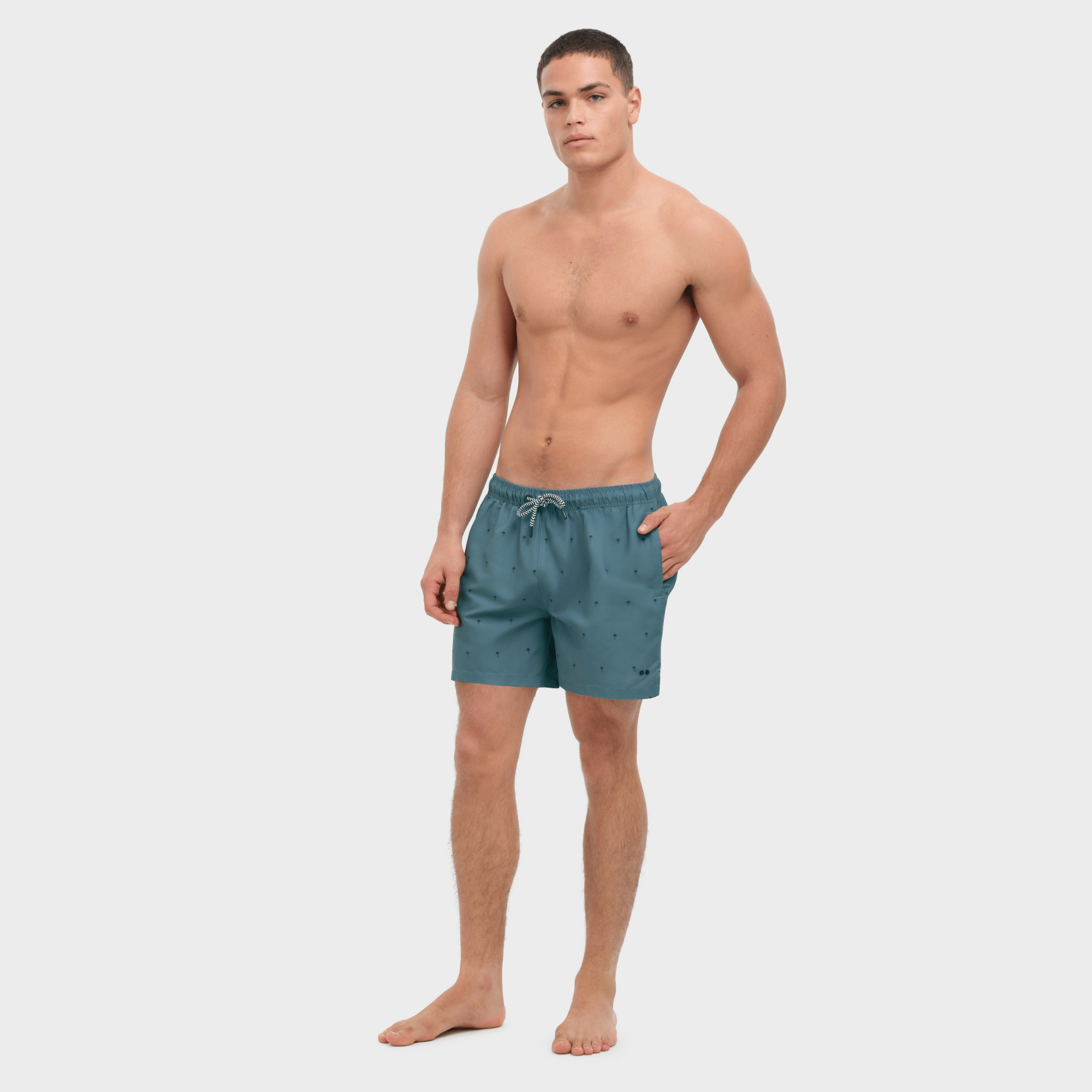 Man wearing teal swim shorts on a white background