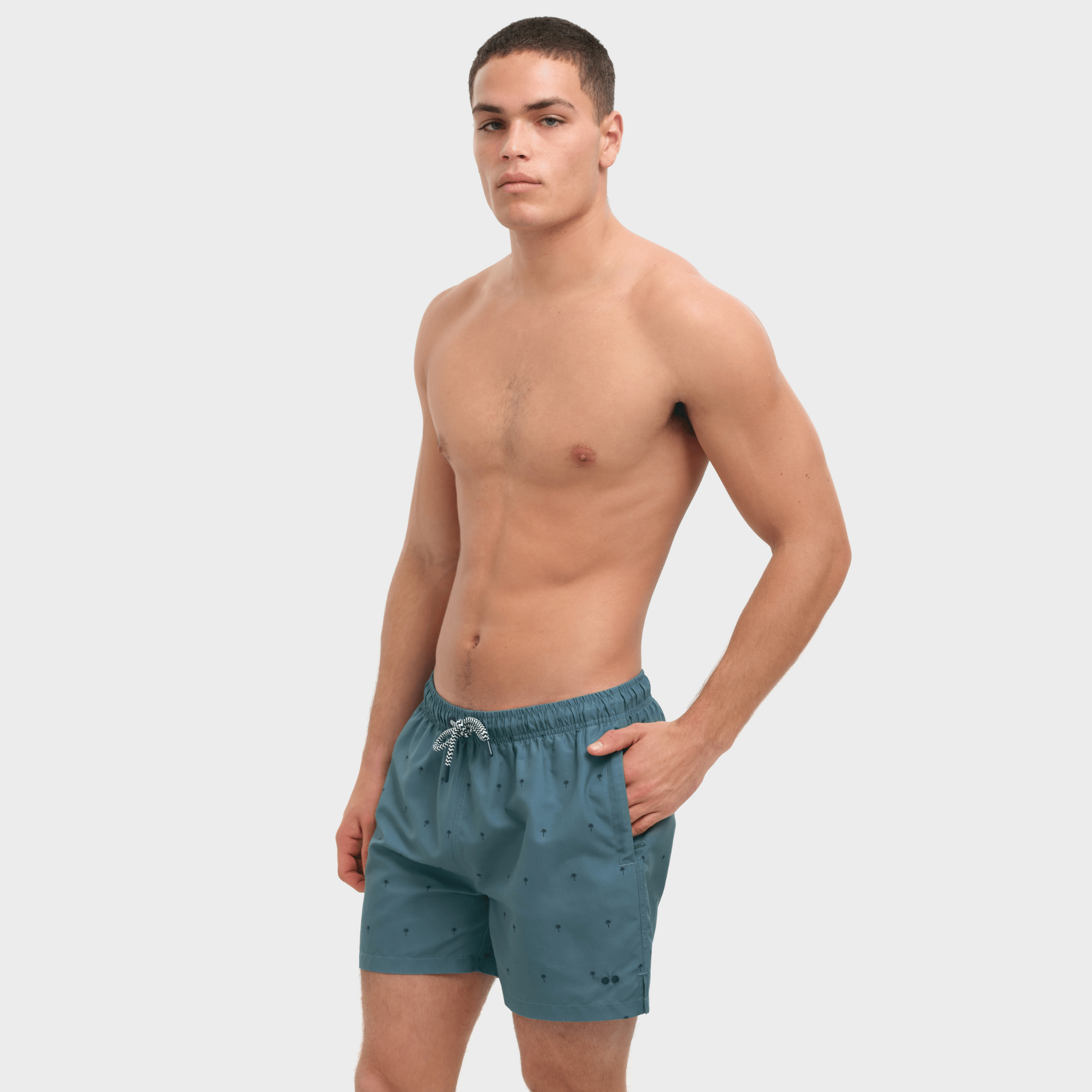 Man wearing teal swim shorts on a white background