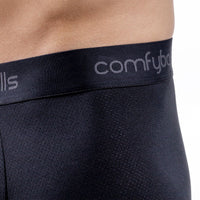 Close-up of a person wearing black mesh boxer briefs with a black elastic waistband featuring the visible brand name 'comfyballs' in light gray.