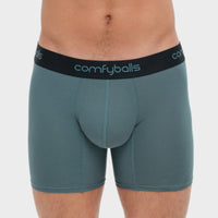 fit:long | qty:1x | menge:1x | A close-up of a man wearing Comfyballs boxer briefs in a muted teal-green color with a black elastic waistband featuring the brand name in light blue.