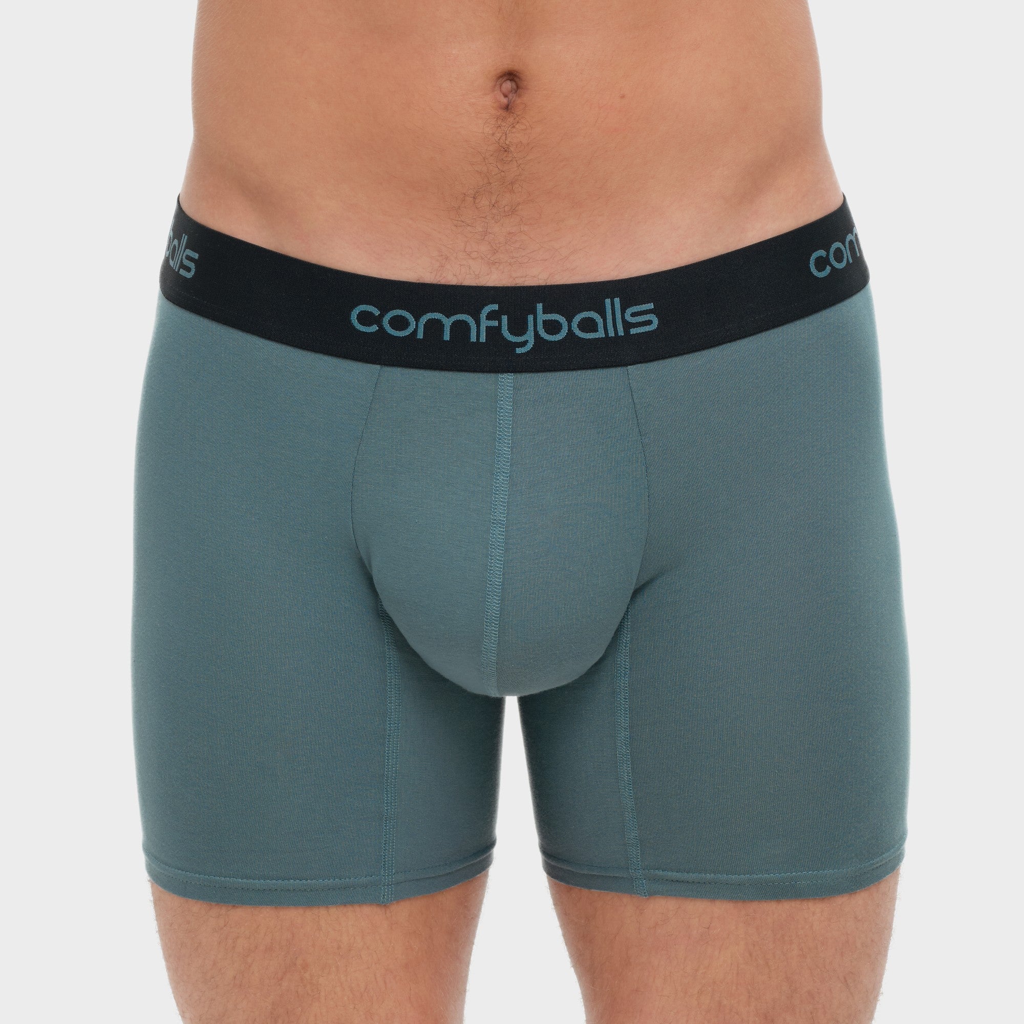 fit:long | qty:1x | menge:1x | A close-up of a man wearing Comfyballs boxer briefs in a muted teal-green color with a black elastic waistband featuring the brand name in light blue.